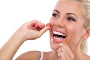 Woman flossing her teeth at dentist in Montrose.